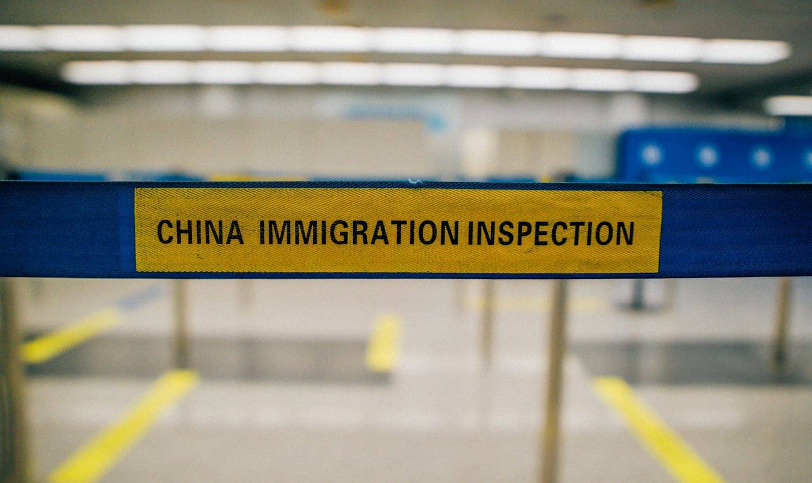 Лента ограждения с надписью China Immigration Inspection в зале паспортного контроля